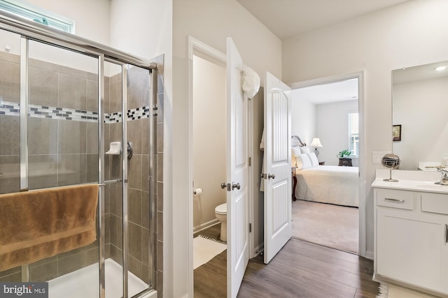 bathroom featuring wood-type flooring, an enclosed shower, vanity, and toilet