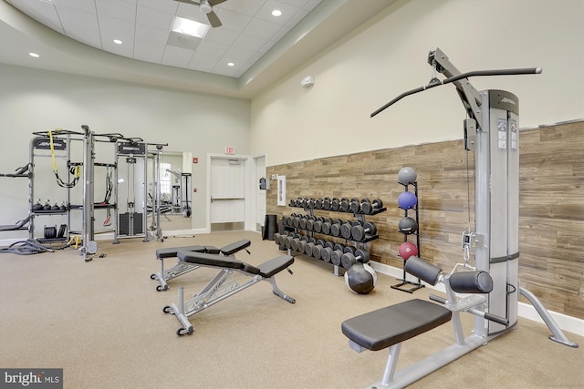 workout area featuring wood walls, a paneled ceiling, and a high ceiling