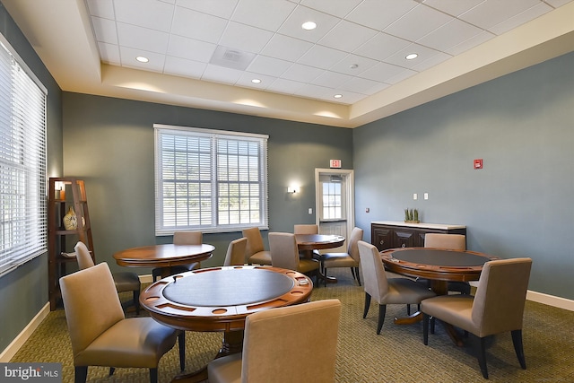 carpeted dining space with a raised ceiling