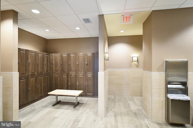 bathroom featuring hardwood / wood-style flooring, tile walls, and a drop ceiling