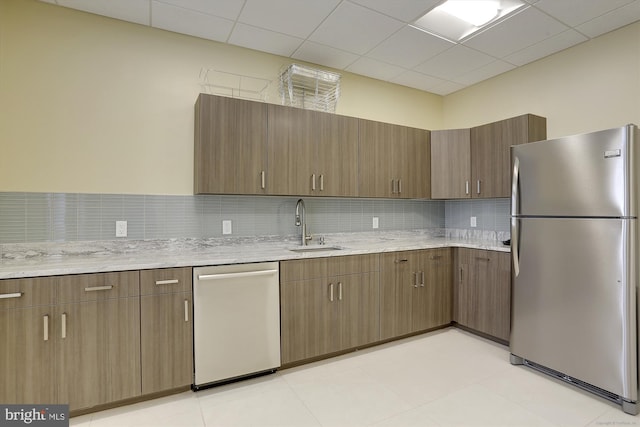 kitchen featuring tasteful backsplash, a drop ceiling, sink, stainless steel appliances, and light tile patterned floors