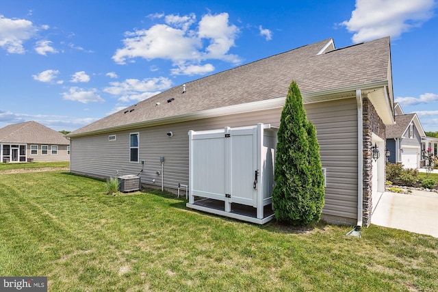 rear view of house with cooling unit and a lawn