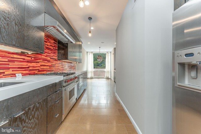 kitchen with wall chimney range hood, light tile patterned floors, designer range, decorative light fixtures, and backsplash