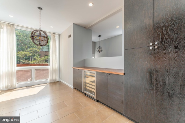 interior space with light tile patterned flooring, beverage cooler, decorative light fixtures, and wood counters