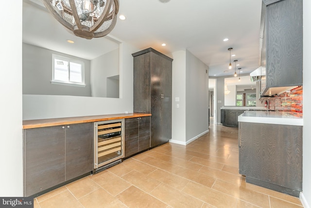 kitchen with wine cooler, light tile patterned flooring, kitchen peninsula, and decorative backsplash