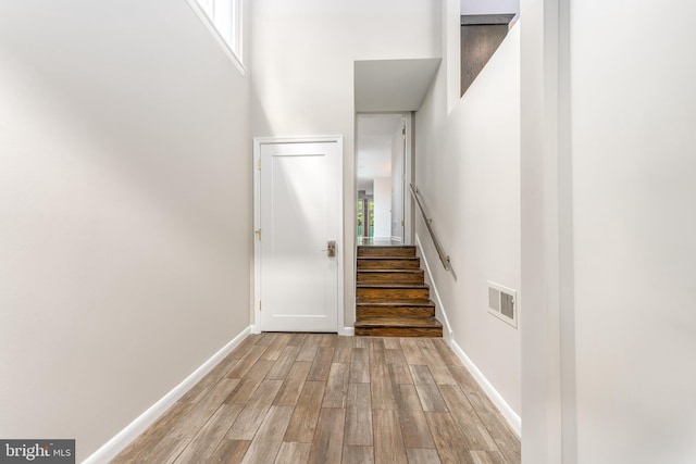 stairs with wood-type flooring and a high ceiling