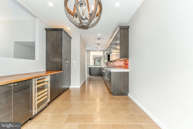 kitchen featuring dark brown cabinets, light tile patterned flooring, wine cooler, and an inviting chandelier