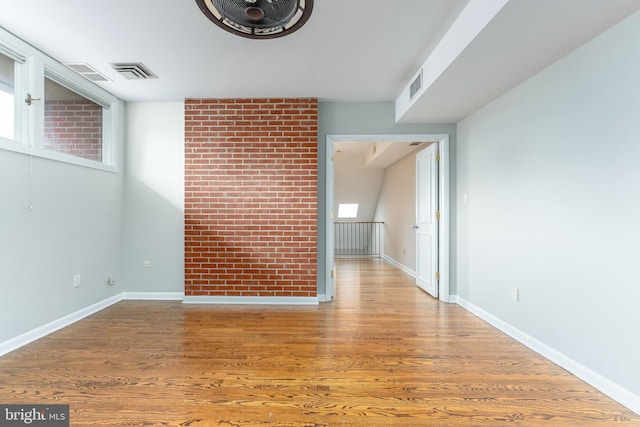 unfurnished living room with hardwood / wood-style floors and brick wall