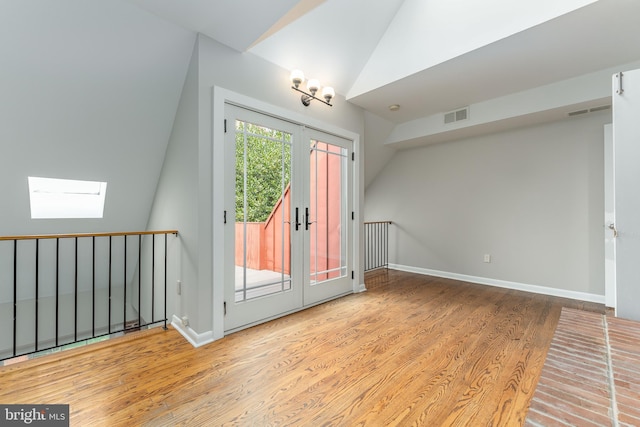 interior space with french doors, vaulted ceiling with skylight, and light hardwood / wood-style floors