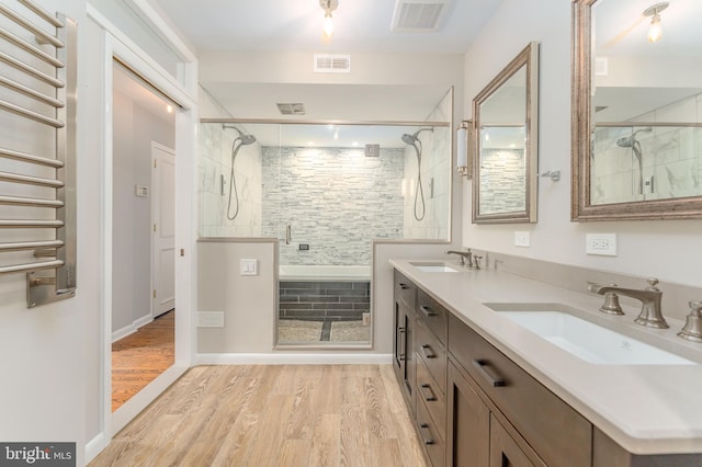 bathroom with a shower with shower door, double sink vanity, and hardwood / wood-style flooring