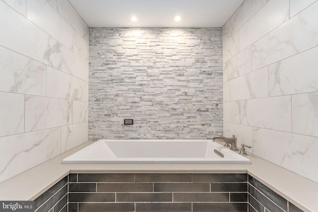 bathroom with tiled tub and tile walls