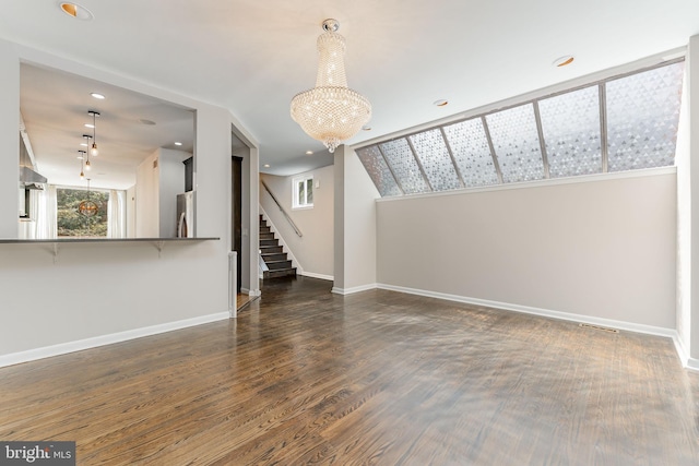 unfurnished living room featuring wood-type flooring, a chandelier, and vaulted ceiling