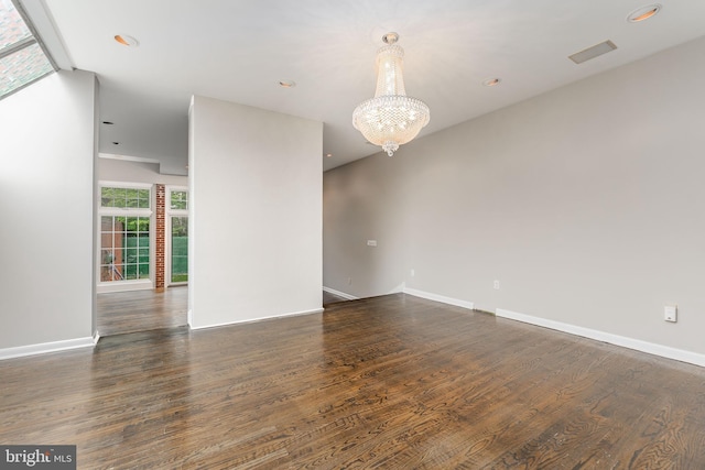 unfurnished room featuring an inviting chandelier and dark hardwood / wood-style flooring