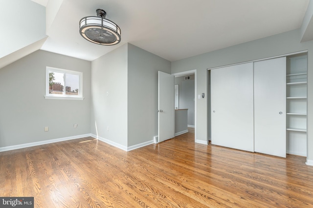 unfurnished bedroom featuring vaulted ceiling, hardwood / wood-style flooring, and a closet