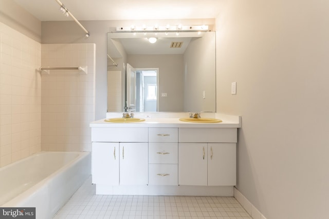 bathroom with dual bowl vanity, tiled shower / bath combo, and tile patterned flooring