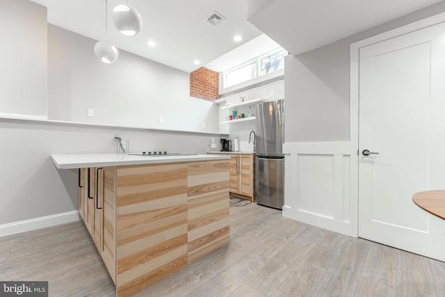 kitchen with decorative light fixtures, stainless steel fridge, light hardwood / wood-style floors, kitchen peninsula, and light brown cabinets