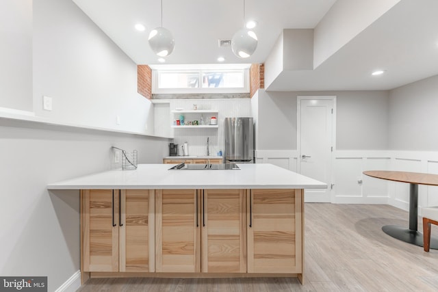 kitchen featuring light brown cabinetry, hanging light fixtures, light hardwood / wood-style floors, and kitchen peninsula