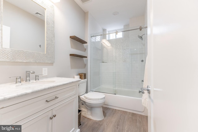 full bathroom featuring hardwood / wood-style flooring, vanity, combined bath / shower with glass door, and toilet