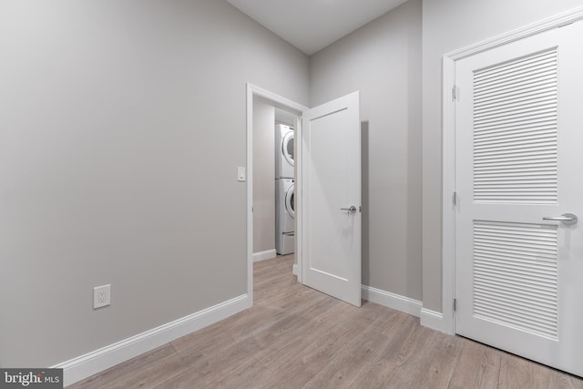 corridor featuring light wood-type flooring and stacked washer and clothes dryer