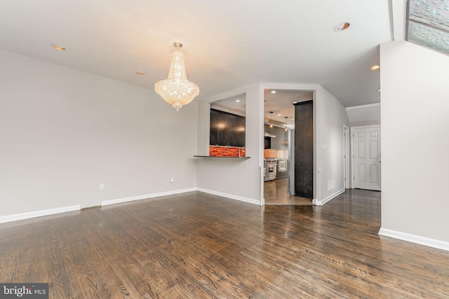 unfurnished living room featuring a notable chandelier, vaulted ceiling, and dark hardwood / wood-style flooring