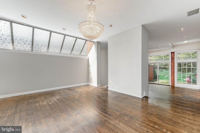 spare room with hardwood / wood-style floors and a chandelier