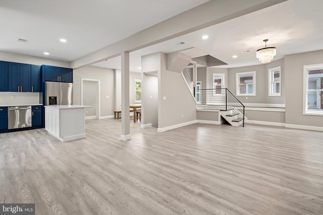 kitchen featuring blue cabinetry, light countertops, light wood-style floors, appliances with stainless steel finishes, and open floor plan