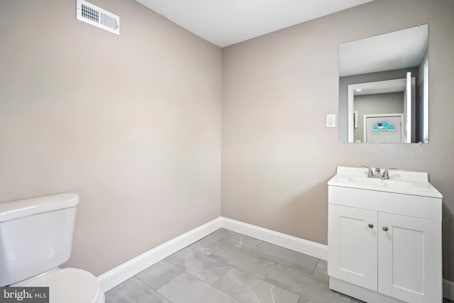 half bath with visible vents, toilet, vanity, and baseboards