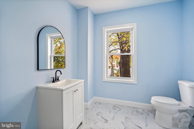 half bath featuring baseboards, toilet, marble finish floor, and vanity