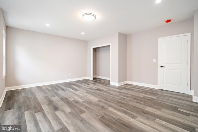 unfurnished bedroom with a closet, recessed lighting, baseboards, and wood finished floors