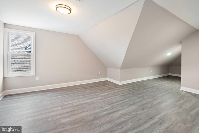 additional living space with vaulted ceiling, wood finished floors, and baseboards