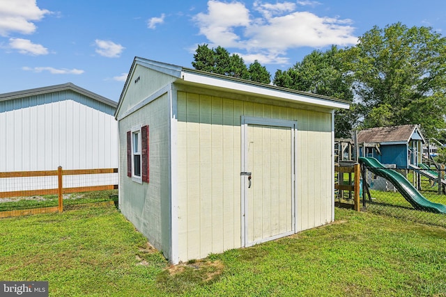 view of outbuilding featuring a playground and a yard