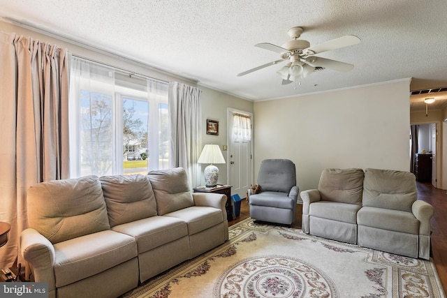 living room with a textured ceiling, wood-type flooring, ceiling fan, and crown molding