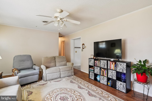 living room featuring hardwood / wood-style flooring, a textured ceiling, ornamental molding, and ceiling fan