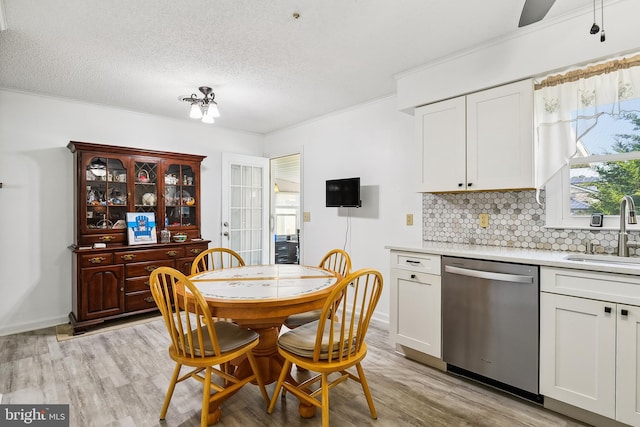 dining room featuring crown molding, light hardwood / wood-style flooring, sink, and a textured ceiling