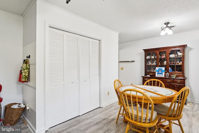 dining space featuring light hardwood / wood-style flooring, a textured ceiling, and crown molding