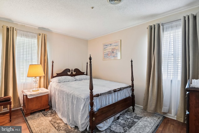 bedroom featuring multiple windows, light wood-type flooring, and a textured ceiling