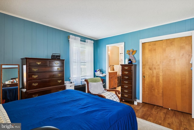 bedroom featuring a closet, wood-type flooring, ensuite bathroom, and a textured ceiling