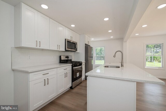 kitchen with white cabinetry, light wood-type flooring, backsplash, stainless steel appliances, and sink