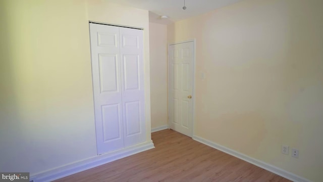 unfurnished bedroom featuring light hardwood / wood-style flooring and a closet