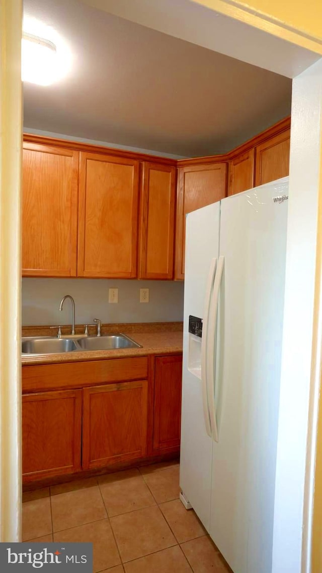 kitchen featuring light tile patterned flooring, sink, and white fridge with ice dispenser