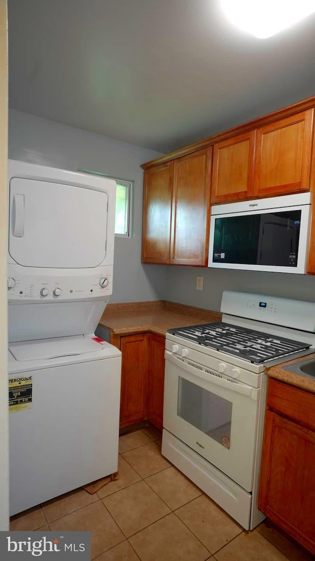 kitchen with stacked washer / drying machine, gas range gas stove, and light tile patterned flooring