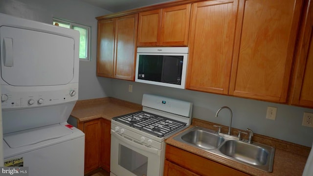 kitchen featuring stacked washer / drying machine, sink, and white range with gas stovetop