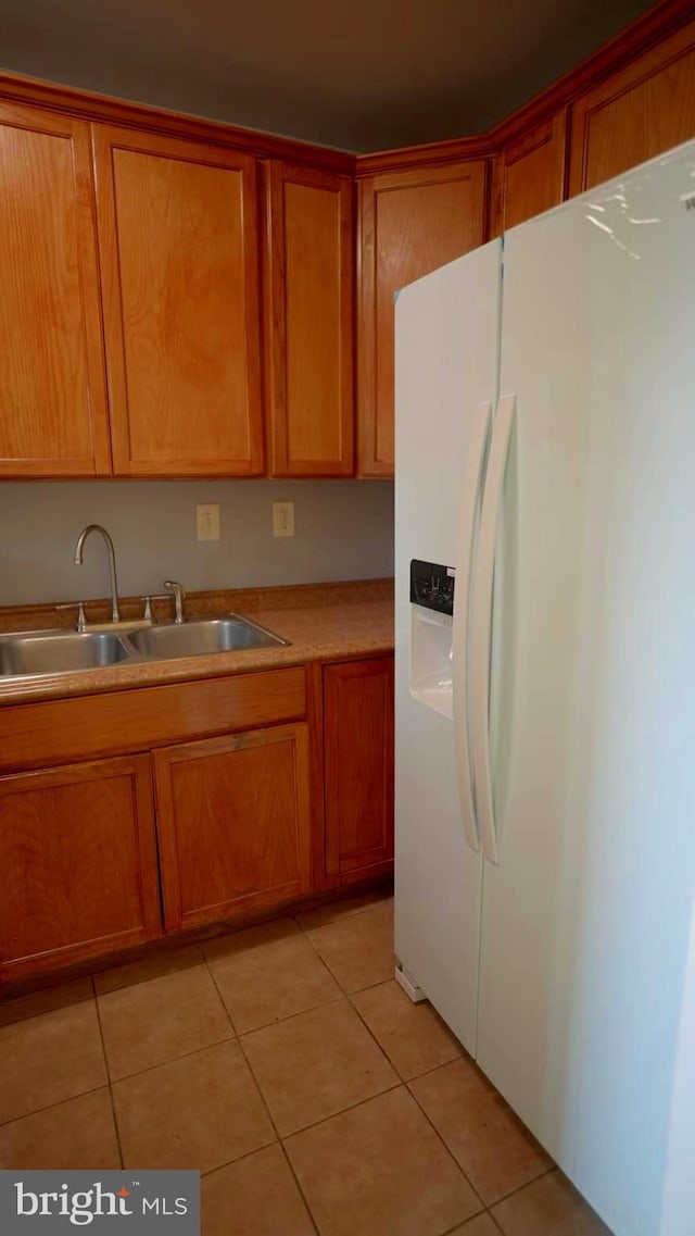 kitchen featuring light tile patterned floors, sink, and white fridge with ice dispenser