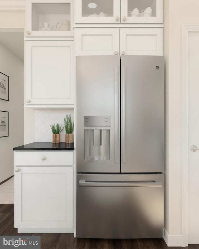 kitchen with dark stone countertops, decorative backsplash, dark hardwood / wood-style flooring, white cabinetry, and stainless steel fridge