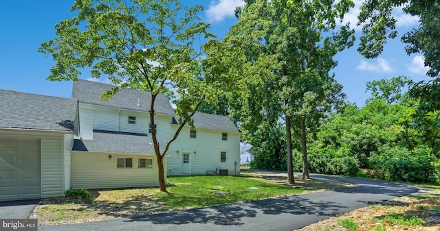 exterior space with central AC unit, a yard, and a garage