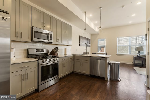 kitchen with kitchen peninsula, appliances with stainless steel finishes, gray cabinetry, pendant lighting, and sink