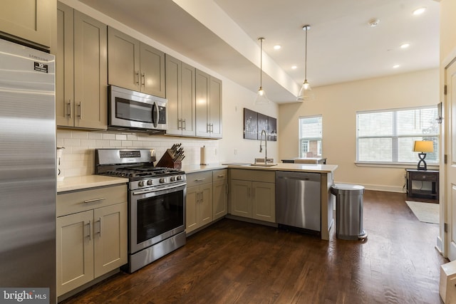 kitchen with decorative light fixtures, stainless steel appliances, sink, dark hardwood / wood-style floors, and kitchen peninsula