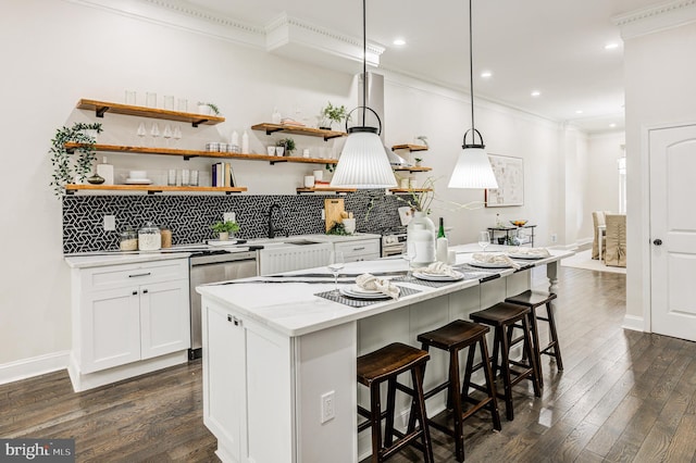 kitchen with decorative backsplash, white cabinets, dark hardwood / wood-style flooring, a kitchen bar, and decorative light fixtures