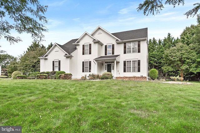 view of front facade featuring a shingled roof and a front lawn