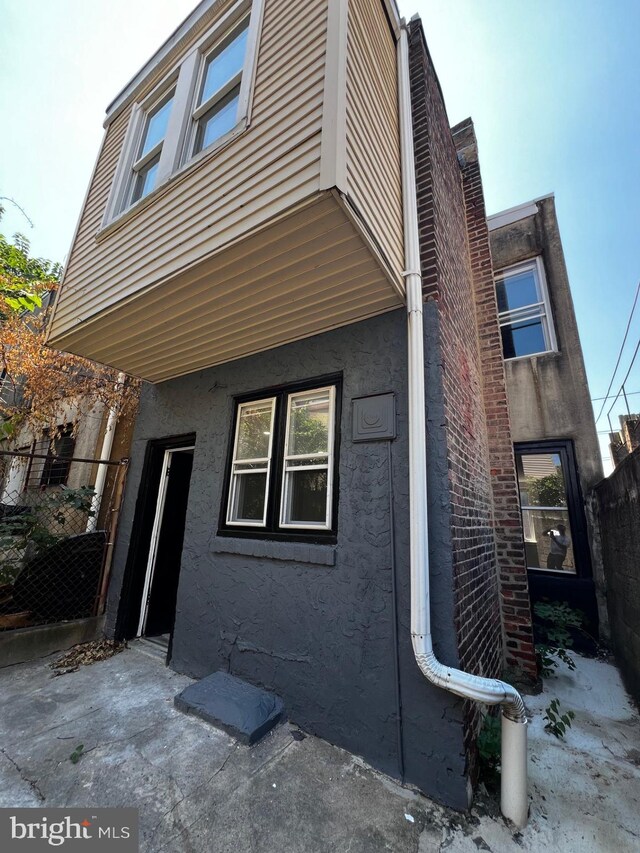 view of side of home featuring stucco siding and fence